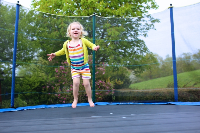 Little girl playing on a trampoline. 