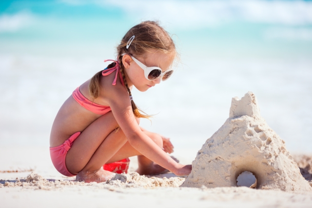 Small girl making a sandcastle in a beach. 