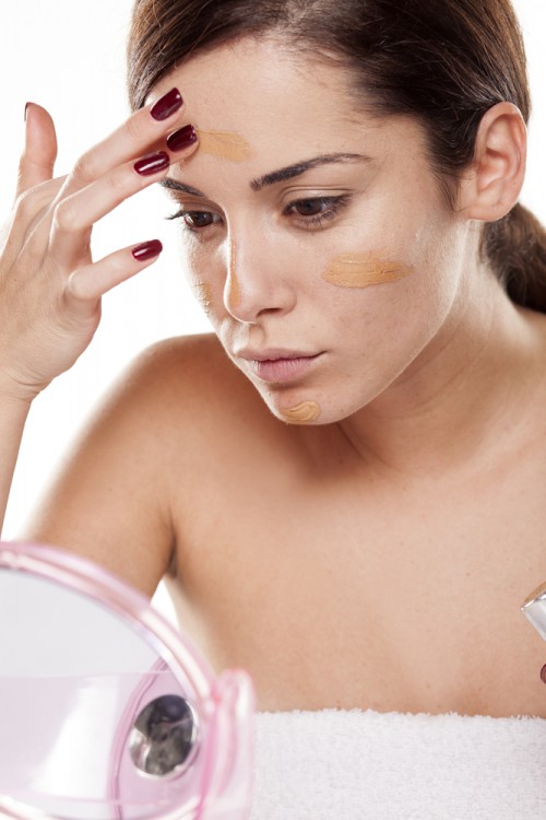 Woman applying a tinted moisturizer on her face. 